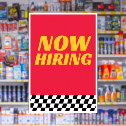 Red 'NOW HIRING' sign with a checkered border in front of shelves with products.
