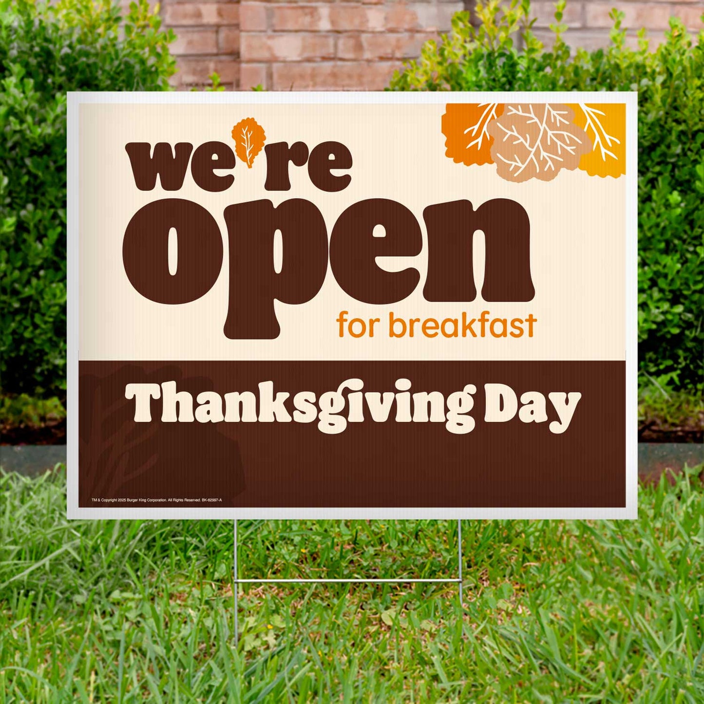 Outdoor sign on grass stating 'we're open for breakfast Thanksgiving Day' with autumn-themed design.