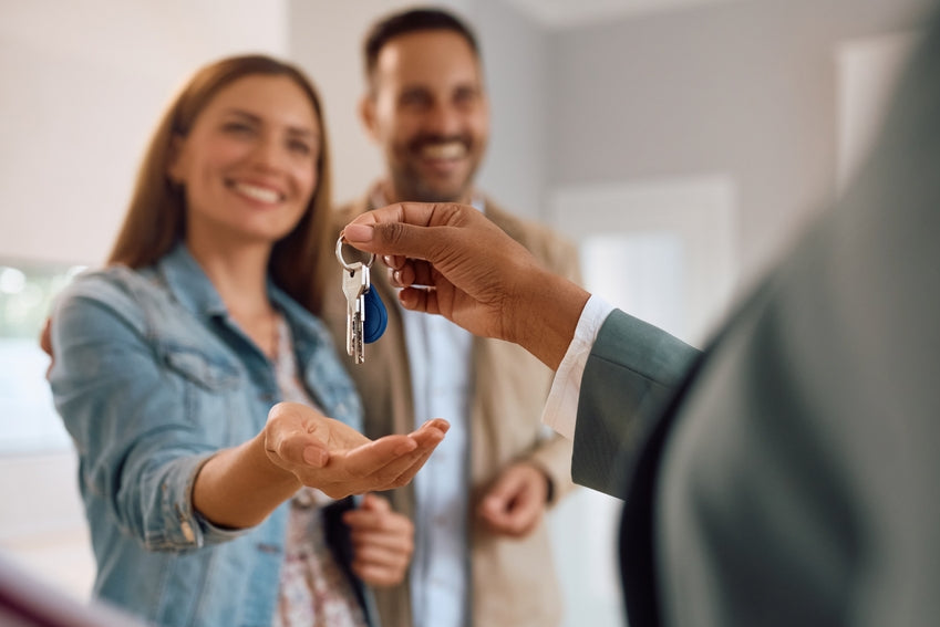 realtor handing keys to smiling couple