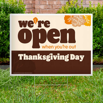 Outdoor sign on grass with 'we're open when you're out Thanksgiving Day' text