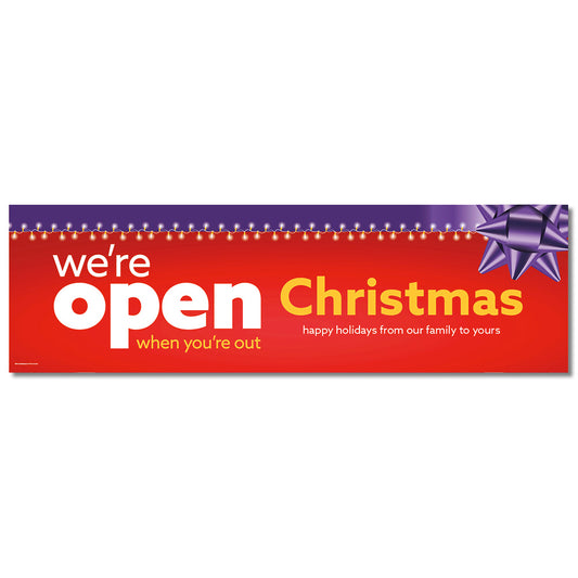 A red banner with white and purple text that reads 'we're open Christmas happy holidays from our family to yours' with a purple ribbon design.